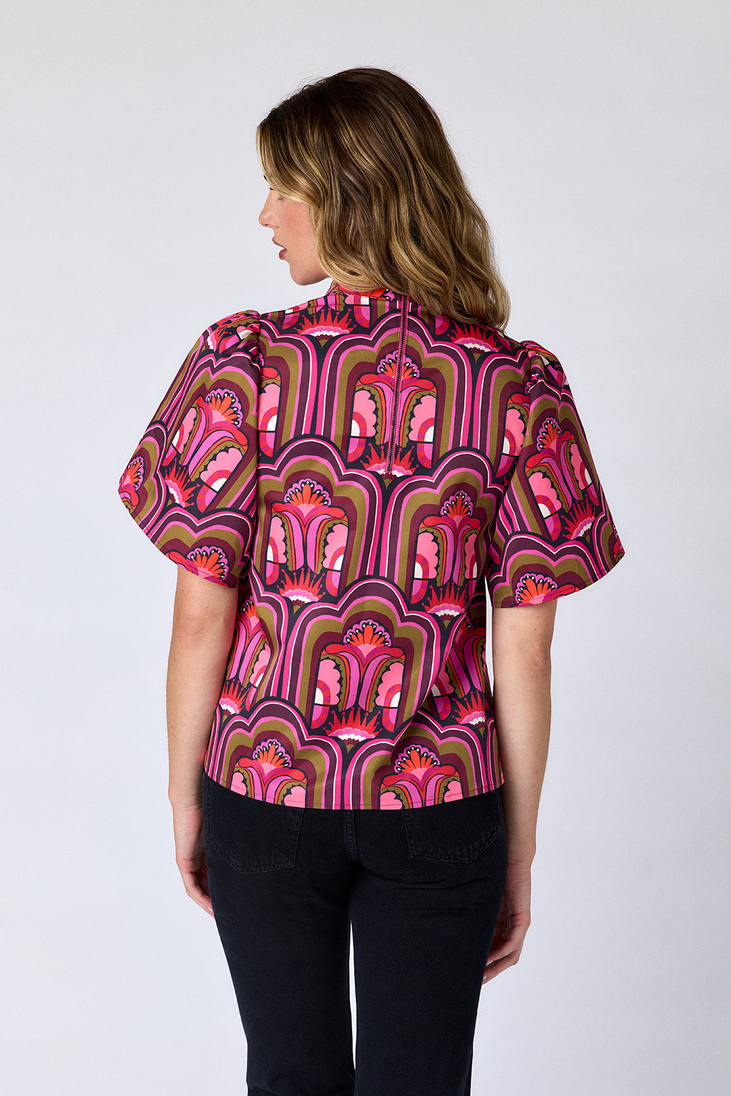 Woman wearing a vibrant, patterned blouse with a white background