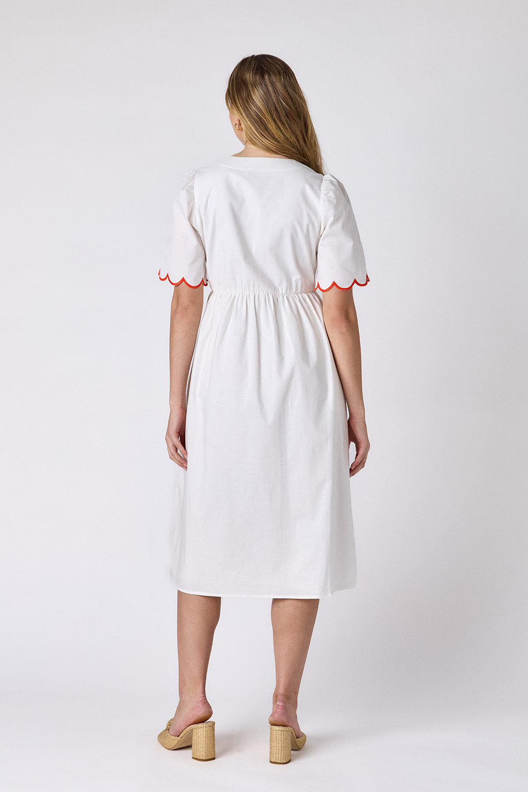 Ivory cotton button-down midi dress with scalloped sleeves and pink and red embroidery on model — CROSBY by Mollie Burch