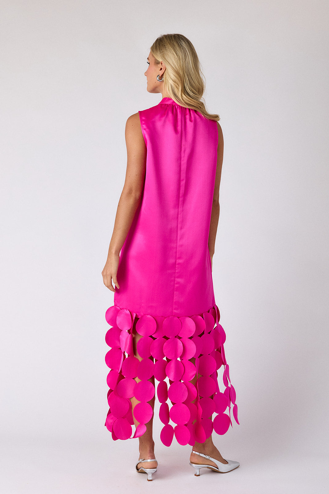 Woman wearing a bright pink dress with unique bottom design on a white background