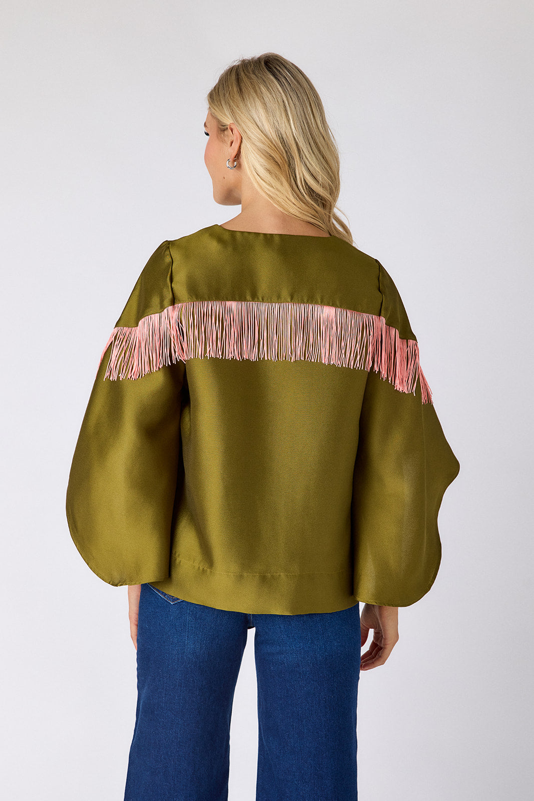 Person wearing a green blouse with pink fringes on a white background