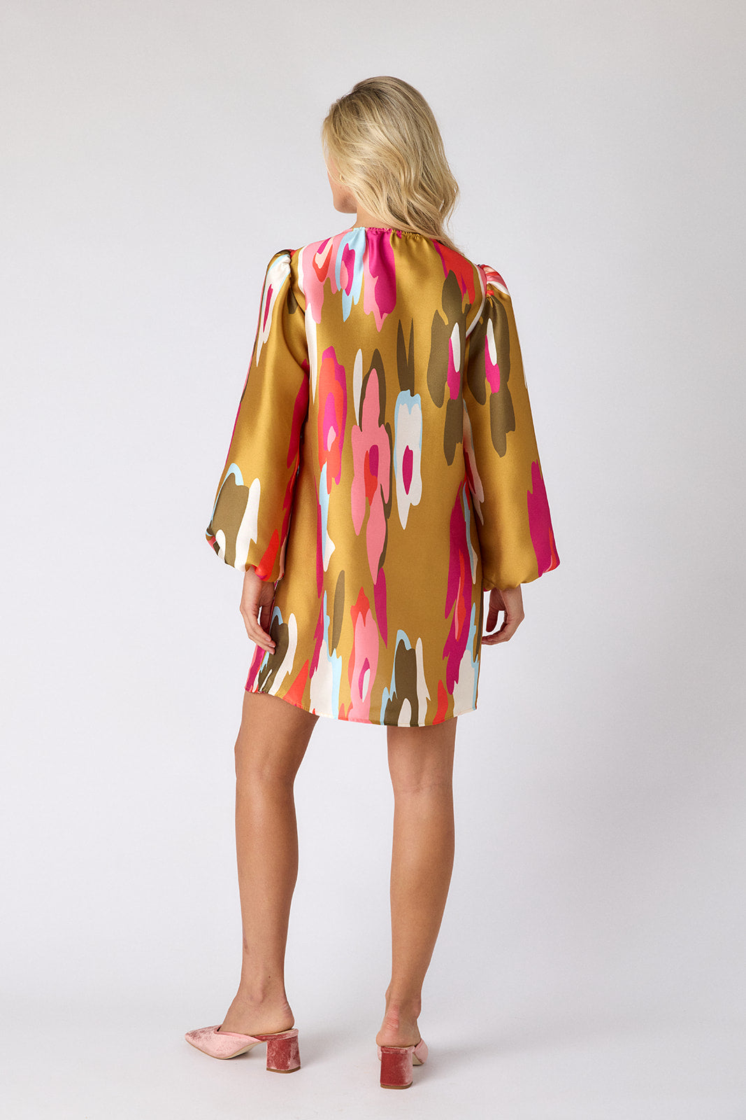 Woman wearing a colorful dress with abstract patterns on a white background