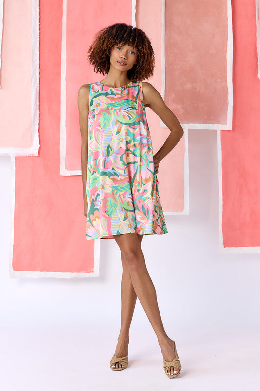 Model wearing an above-the-knee sleeveless shift dress in a vibrant multicolor floral print, featuring a low V-shaped back and button panel detail — CROSBY by Mollie Burch