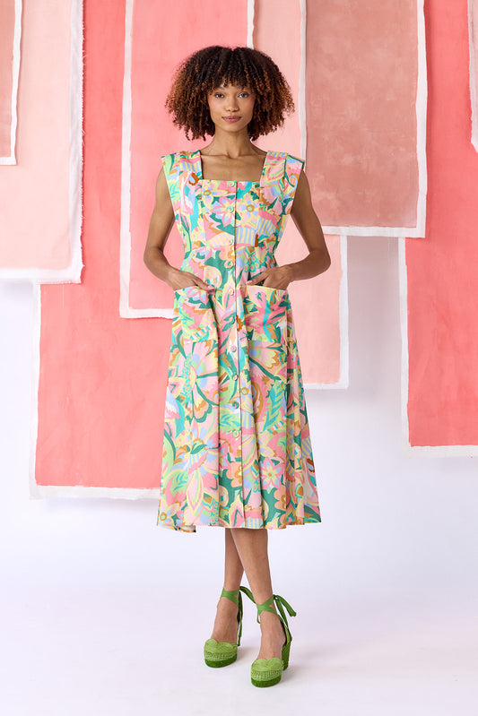 Model wearing a mid-calf length fit-and-flare dress in a vibrant multicolor floral print, featuring a square neckline, cap sleeves, full button front, and a full, swingy skirt — CROSBY by Mollie Burch