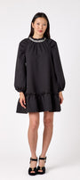 Flynn Dress in Black featuring rhinestone neckline, ruffle hem, and back tie detailing on model – CROSBY by Mollie Burch