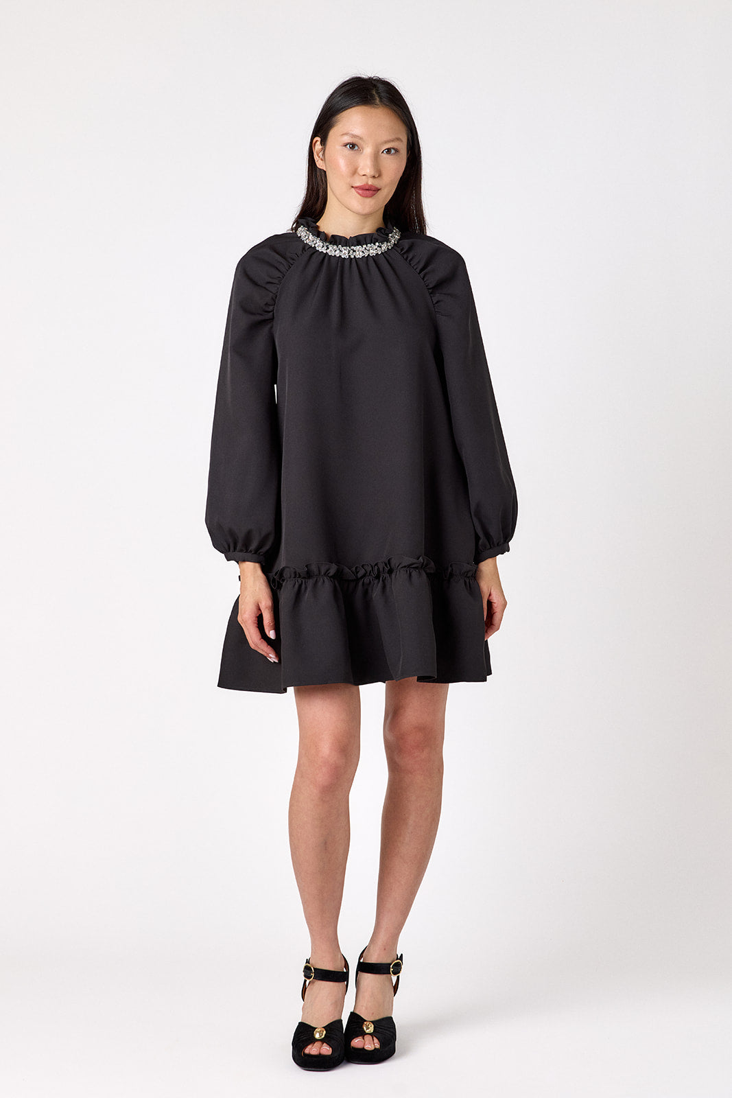 Flynn Dress in Black featuring rhinestone neckline, ruffle hem, and back tie detailing on model – CROSBY by Mollie Burch