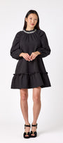 Flynn Dress in Black featuring rhinestone neckline, ruffle hem, and back tie detailing on model – CROSBY by Mollie Burch