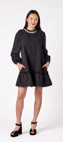 Flynn Dress in Black featuring rhinestone neckline, ruffle hem, and back tie detailing on model – CROSBY by Mollie Burch