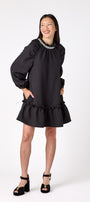 Flynn Dress in Black featuring rhinestone neckline, ruffle hem, and back tie detailing on model – CROSBY by Mollie Burch