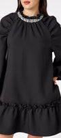 Flynn Dress in Black featuring rhinestone neckline, ruffle hem, and back tie detailing on model – CROSBY by Mollie Burch