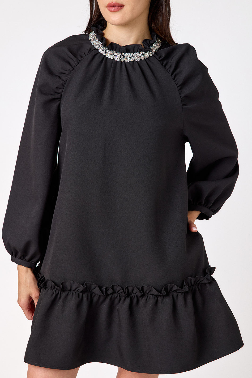 Flynn Dress in Black featuring rhinestone neckline, ruffle hem, and back tie detailing on model – CROSBY by Mollie Burch