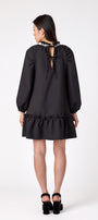 Flynn Dress in Black featuring rhinestone neckline, ruffle hem, and back tie detailing on model – CROSBY by Mollie Burch