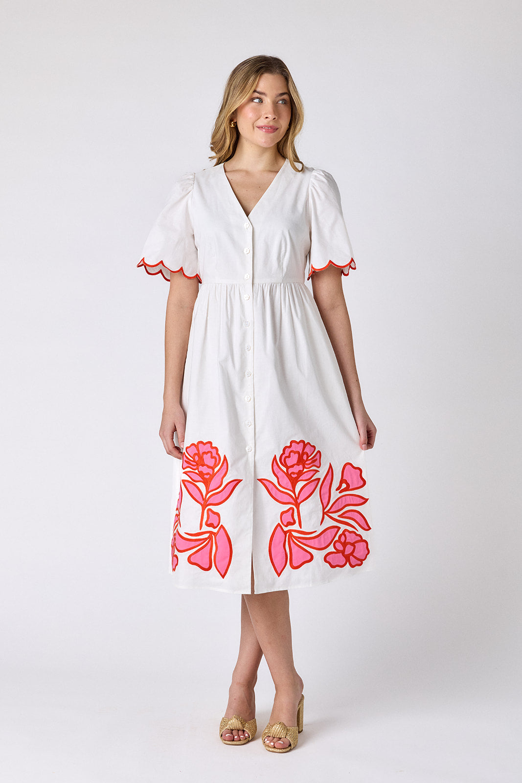 Ivory cotton button-down midi dress with scalloped sleeves and pink and red embroidery on model — CROSBY by Mollie Burch