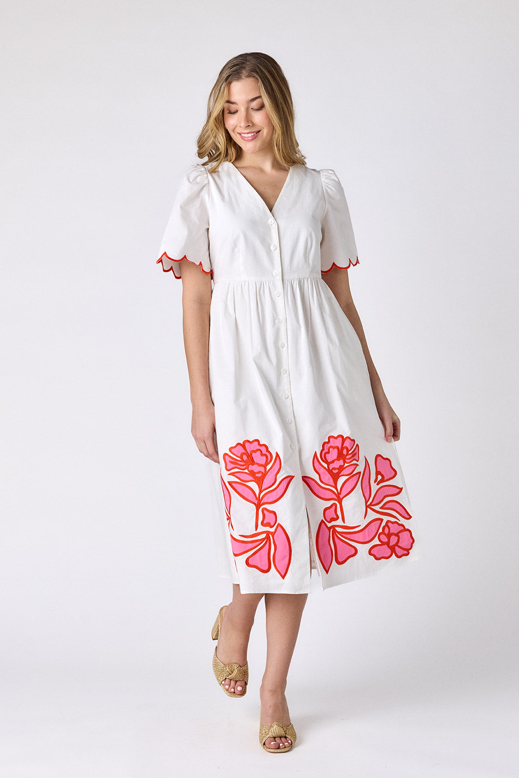 Ivory cotton button-down midi dress with scalloped sleeves and pink and red embroidery on model — CROSBY by Mollie Burch