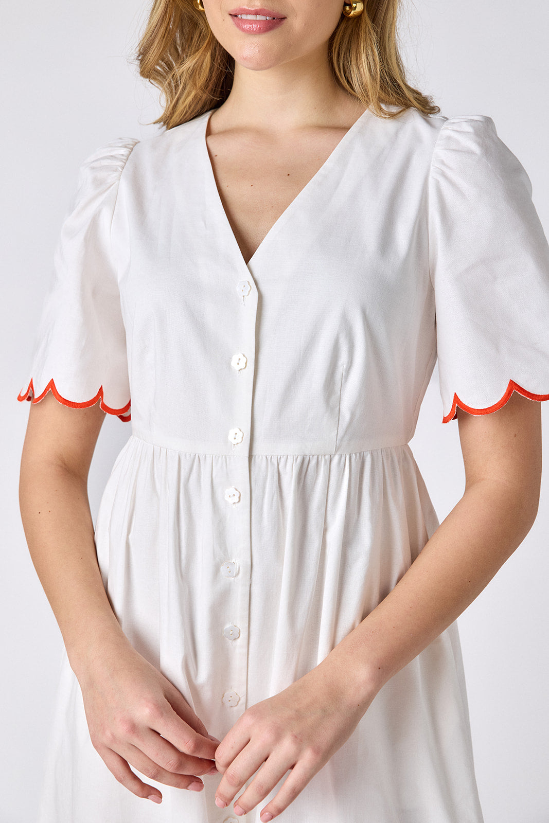 Ivory cotton button-down midi dress with scalloped sleeves and pink and red embroidery on model — CROSBY by Mollie Burch
