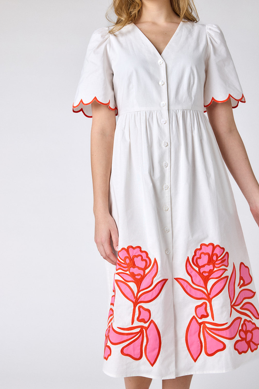 Ivory cotton button-down midi dress with scalloped sleeves and pink and red embroidery on model — CROSBY by Mollie Burch