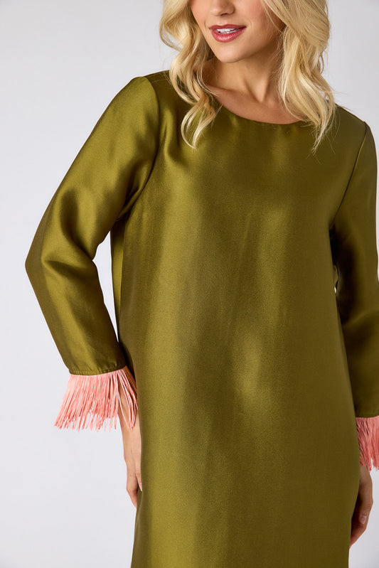 Woman wearing a green dress with pink fringes on a white background