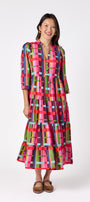 Macrostie Dress in Plaid Parade featuring a colorful plaid print, tiered midi skirt, and gold-accented buttons on model – CROSBY by Mollie Burch