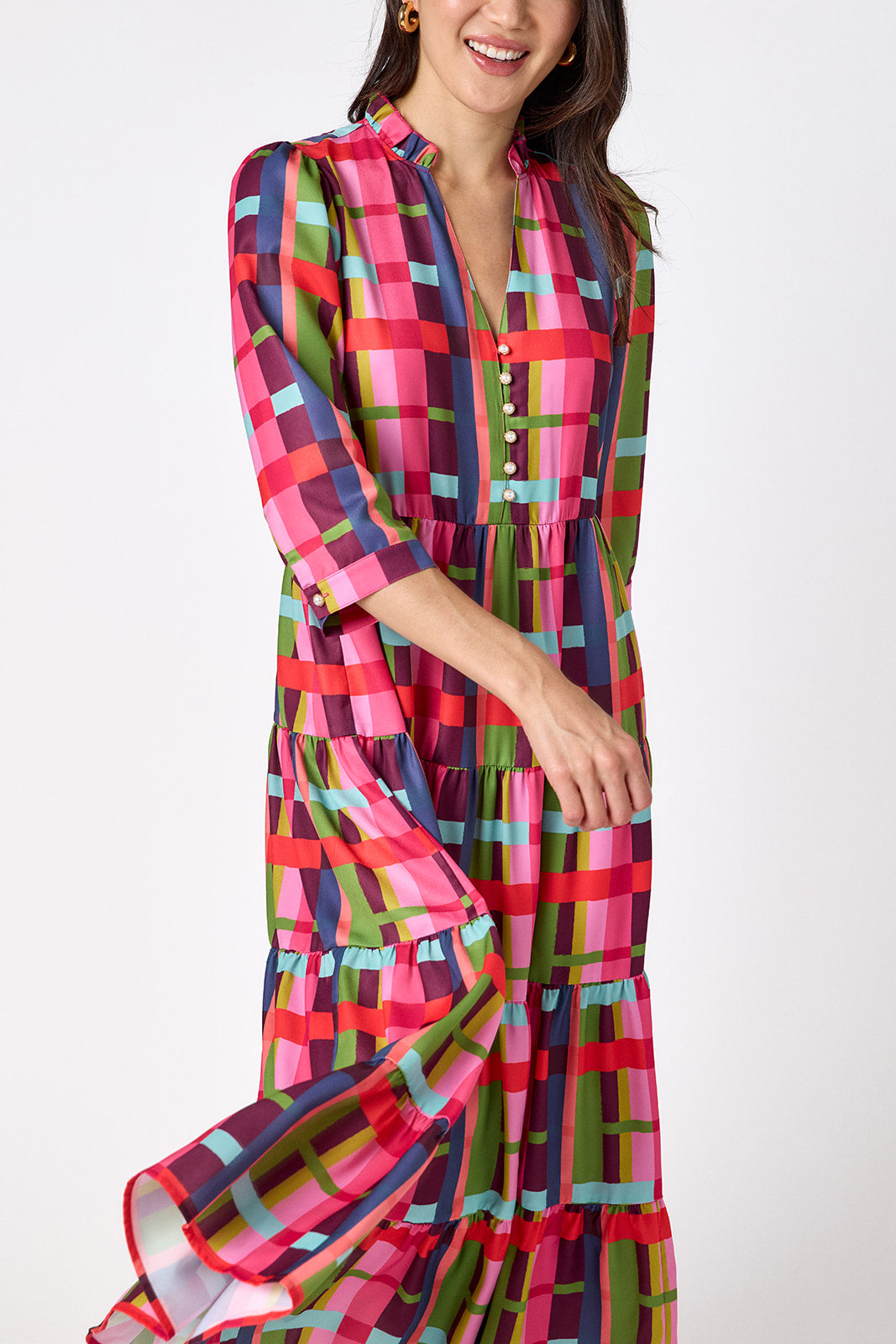 Macrostie Dress in Plaid Parade featuring a colorful plaid print, tiered midi skirt, and gold-accented buttons on model – CROSBY by Mollie Burch