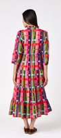 Macrostie Dress in Plaid Parade featuring a colorful plaid print, tiered midi skirt, and gold-accented buttons on model – CROSBY by Mollie Burch