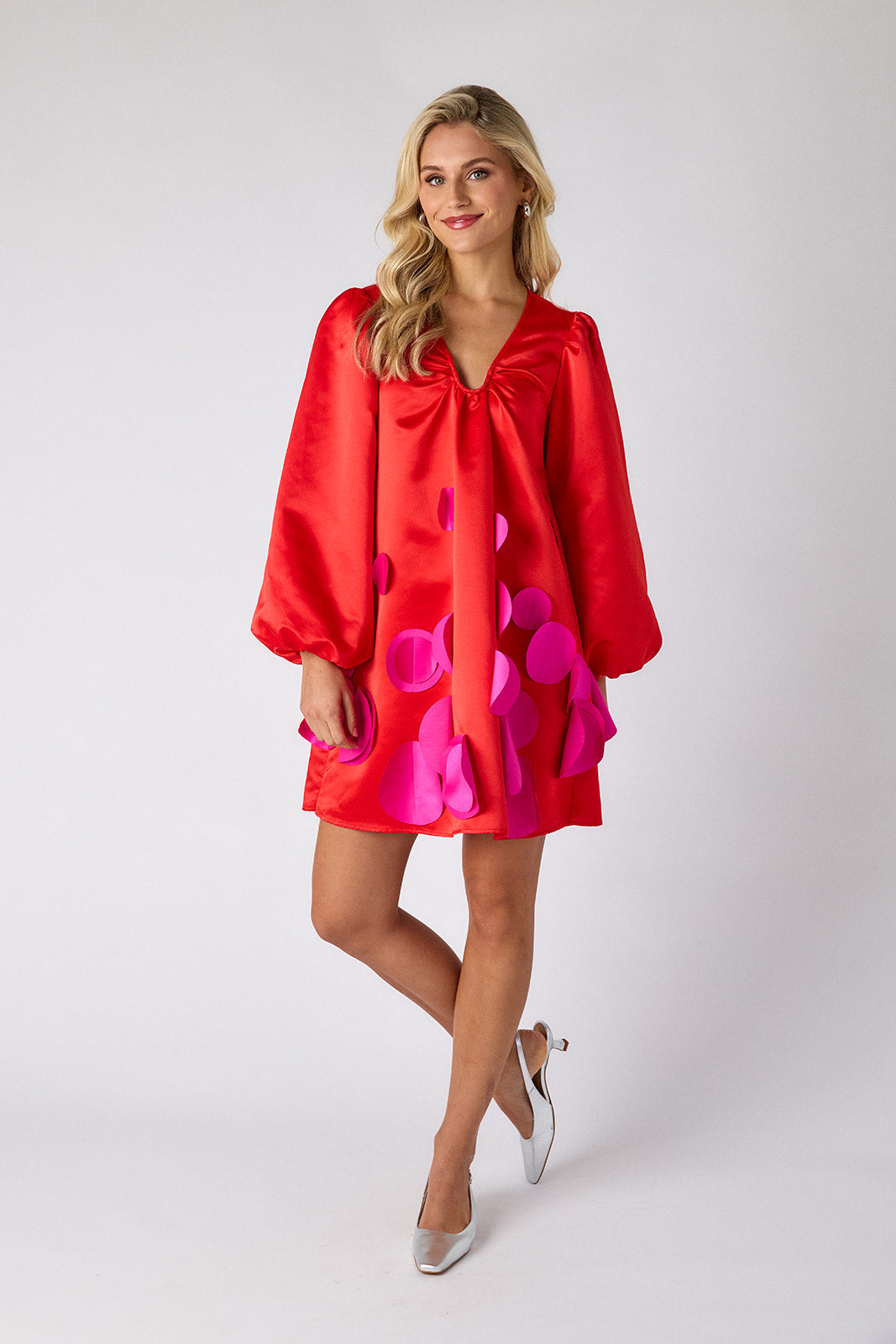 Woman wearing a red dress with pink polka dots on a white background