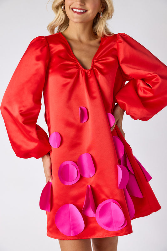 Woman wearing a red dress with pink polka dots on a white background