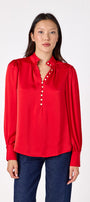 Leland Blouse in Ruby Red featuring puff sleeves and gold-rimmed pearl buttons on model – CROSBY by Mollie Burch