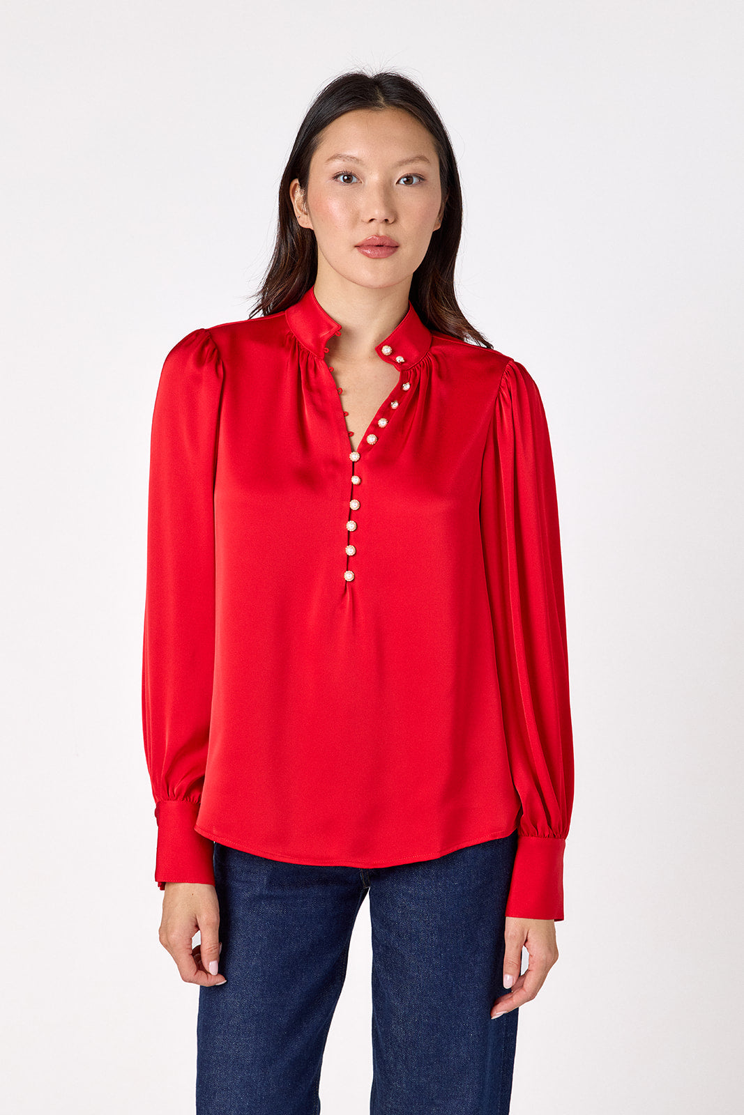 Leland Blouse in Ruby Red featuring puff sleeves and gold-rimmed pearl buttons on model – CROSBY by Mollie Burch