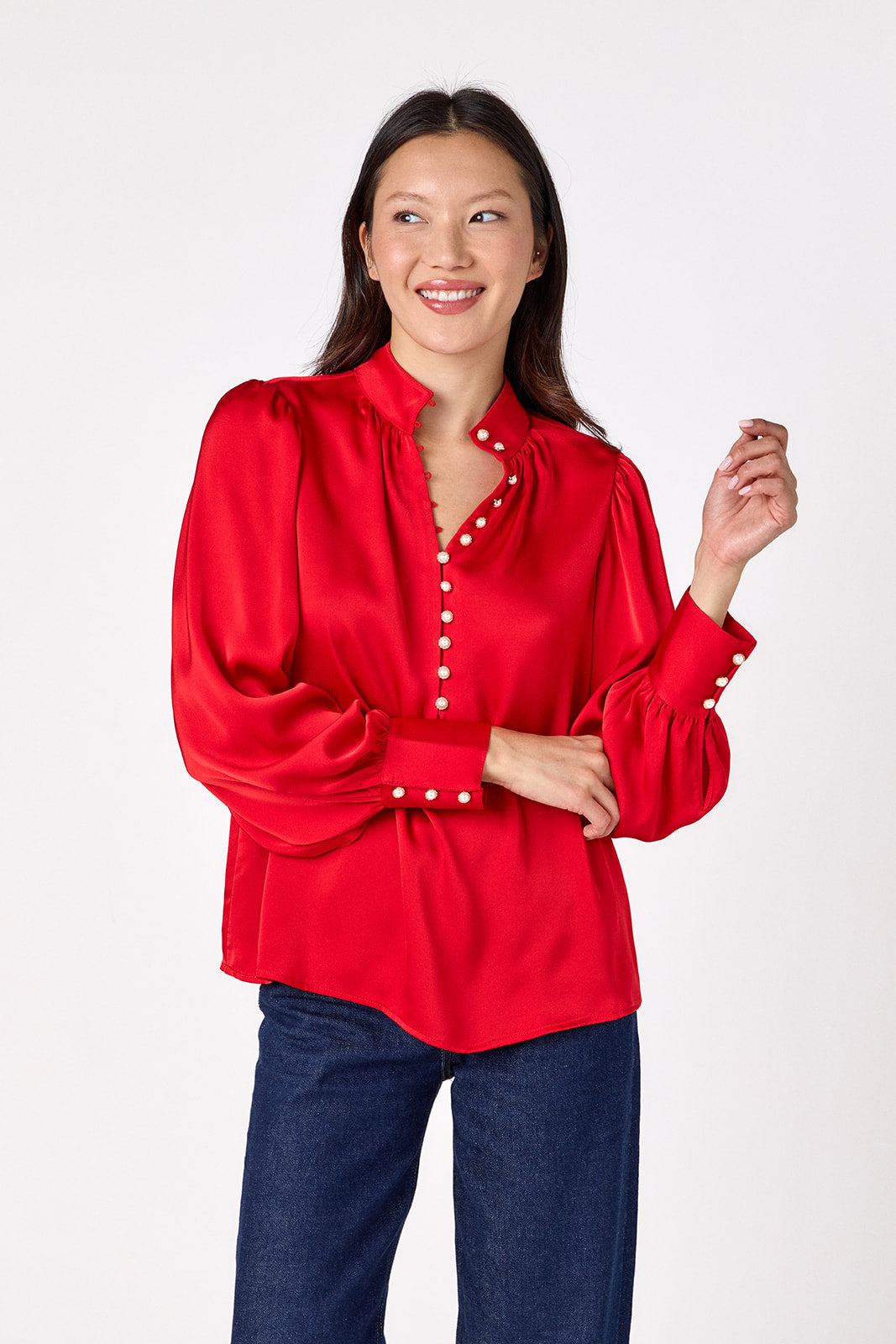 Leland Blouse in Ruby Red featuring puff sleeves and gold-rimmed pearl buttons on model – CROSBY by Mollie Burch