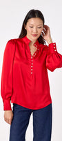 Leland Blouse in Ruby Red featuring puff sleeves and gold-rimmed pearl buttons on model – CROSBY by Mollie Burch