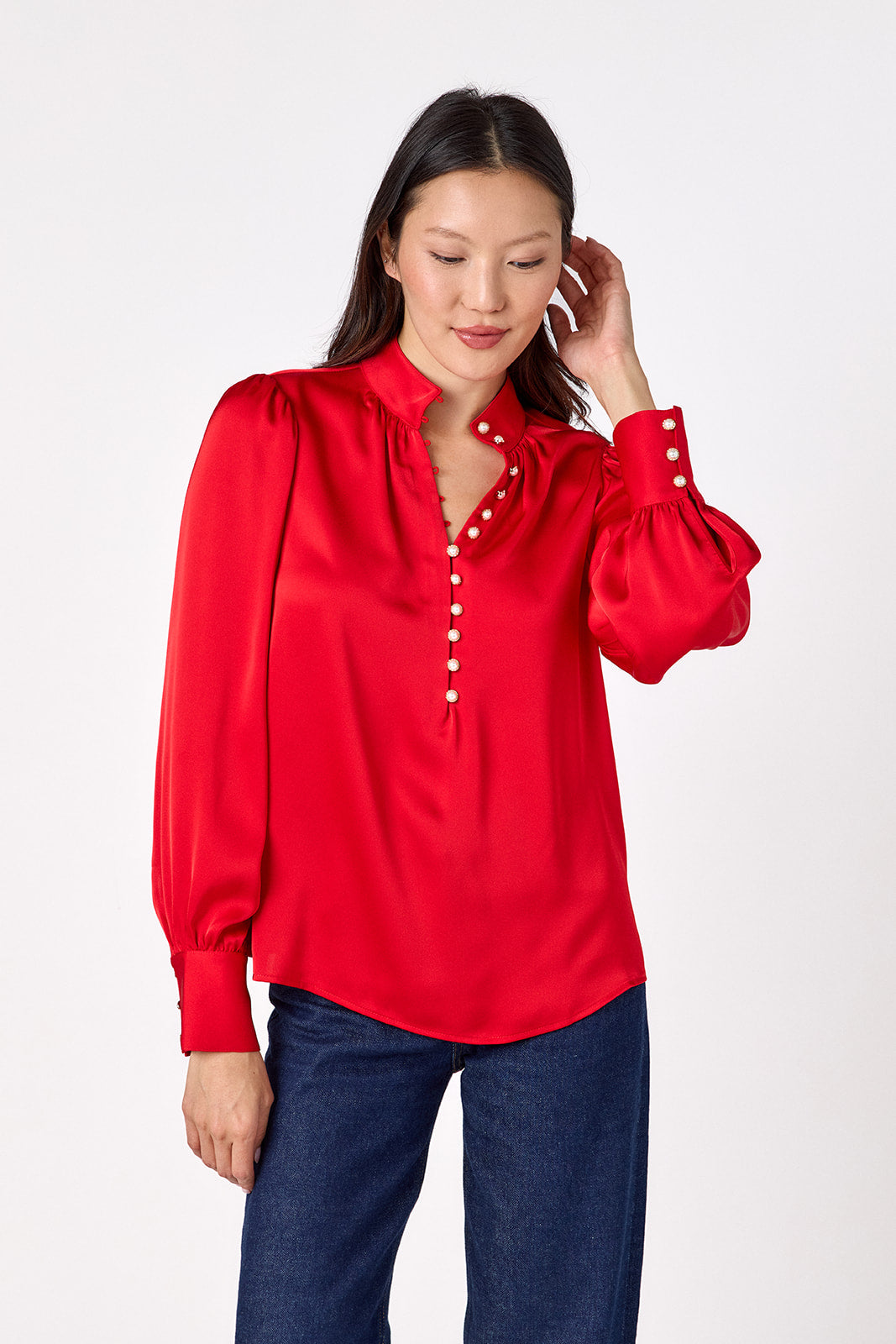 Leland Blouse in Ruby Red featuring puff sleeves and gold-rimmed pearl buttons on model – CROSBY by Mollie Burch