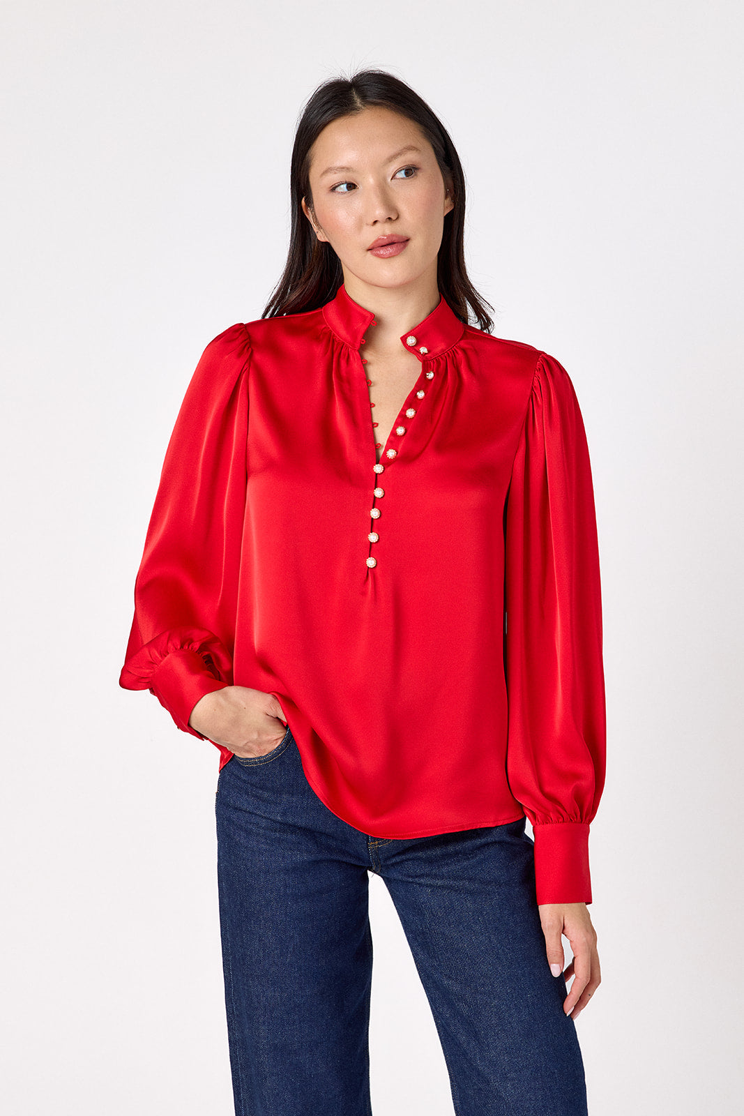 Leland Blouse in Ruby Red featuring puff sleeves and gold-rimmed pearl buttons on model – CROSBY by Mollie Burch