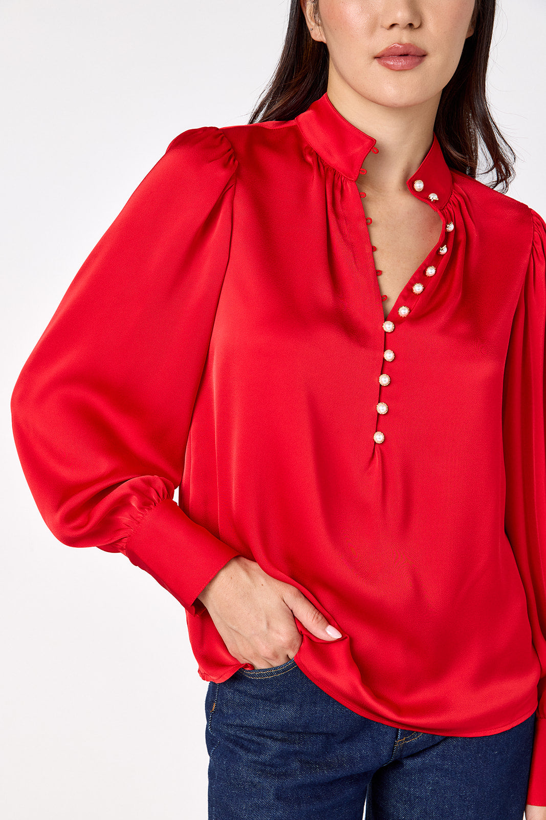 Leland Blouse in Ruby Red featuring puff sleeves and gold-rimmed pearl buttons on model – CROSBY by Mollie Burch