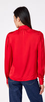 Leland Blouse in Ruby Red featuring puff sleeves and gold-rimmed pearl buttons on model – CROSBY by Mollie Burch