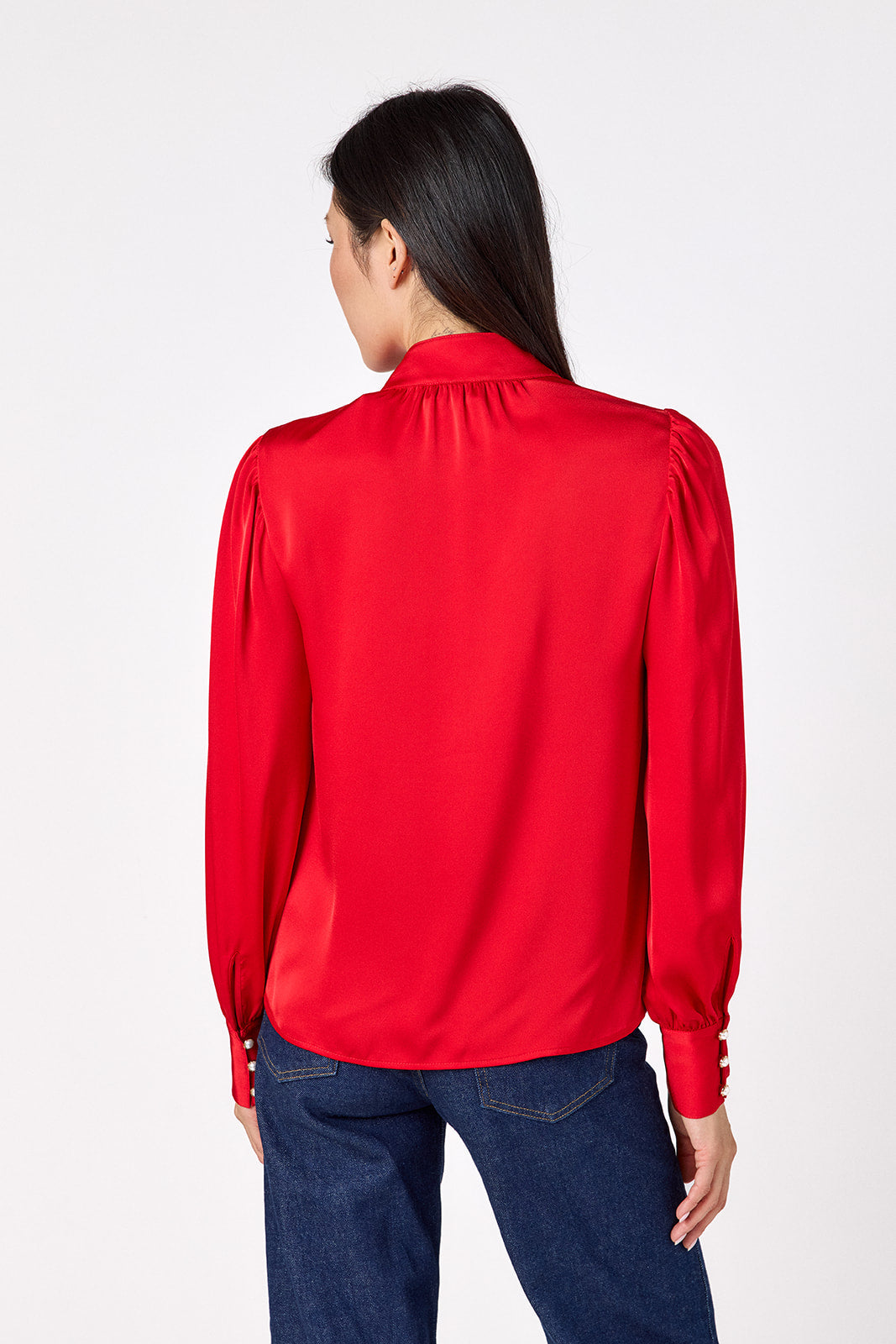 Leland Blouse in Ruby Red featuring puff sleeves and gold-rimmed pearl buttons on model – CROSBY by Mollie Burch
