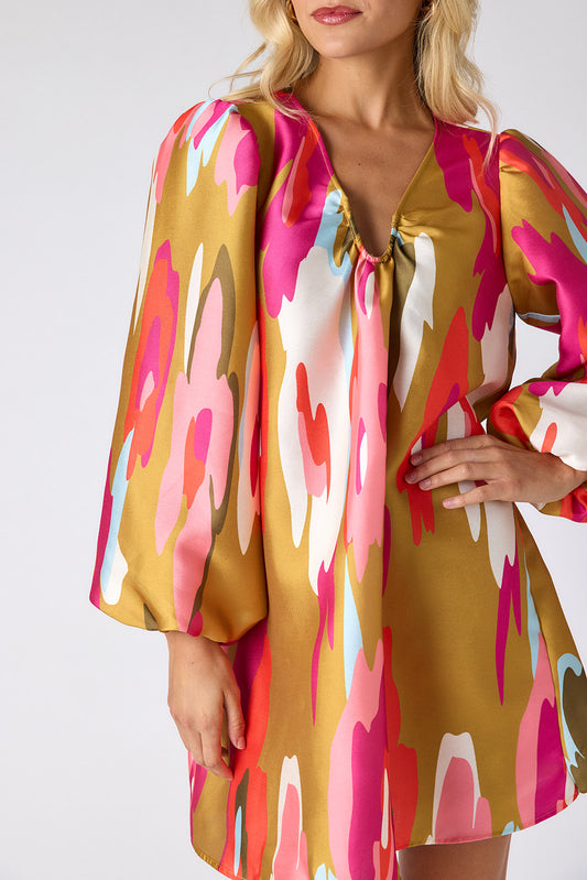 Woman wearing a colorful dress with a pattern of pink, red, and white on a plain background