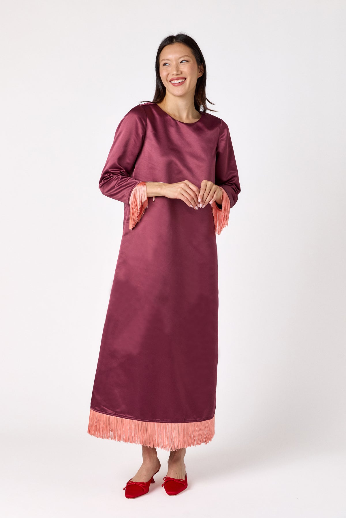 Drewry Dress in Wine featuring satin fabric and contrast fringe trim on model – CROSBY by Mollie Burch