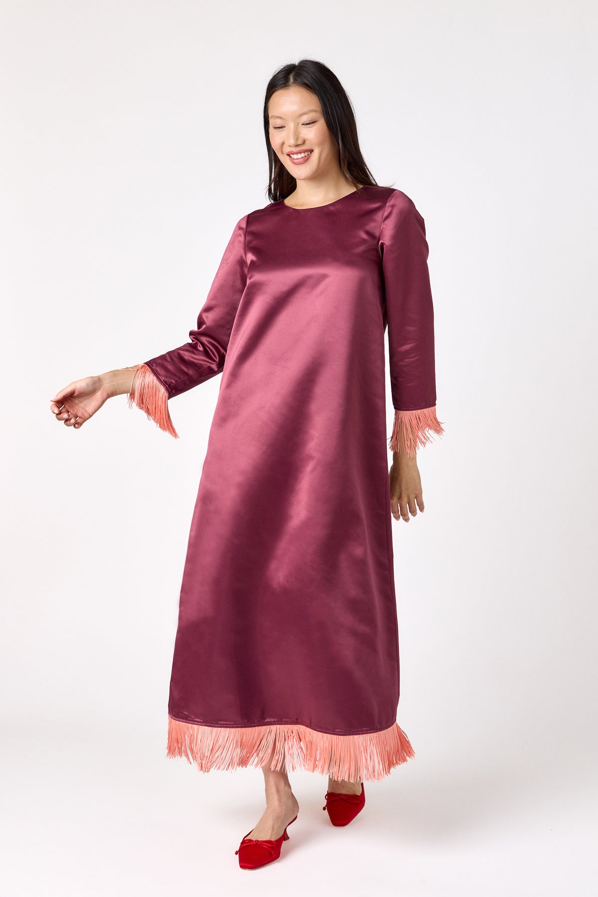 Drewry Dress in Wine featuring satin fabric and contrast fringe trim on model – CROSBY by Mollie Burch