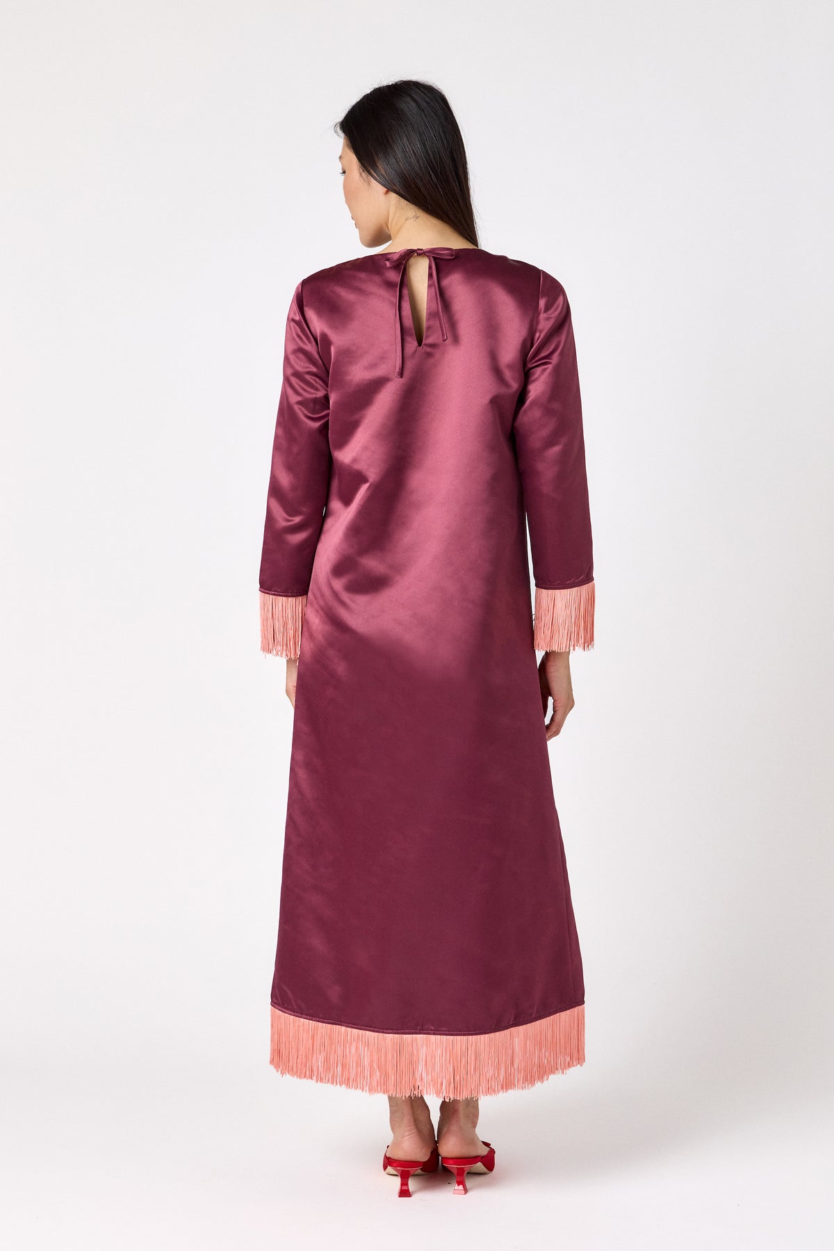 Drewry Dress in Wine featuring satin fabric and contrast fringe trim on model – CROSBY by Mollie Burch