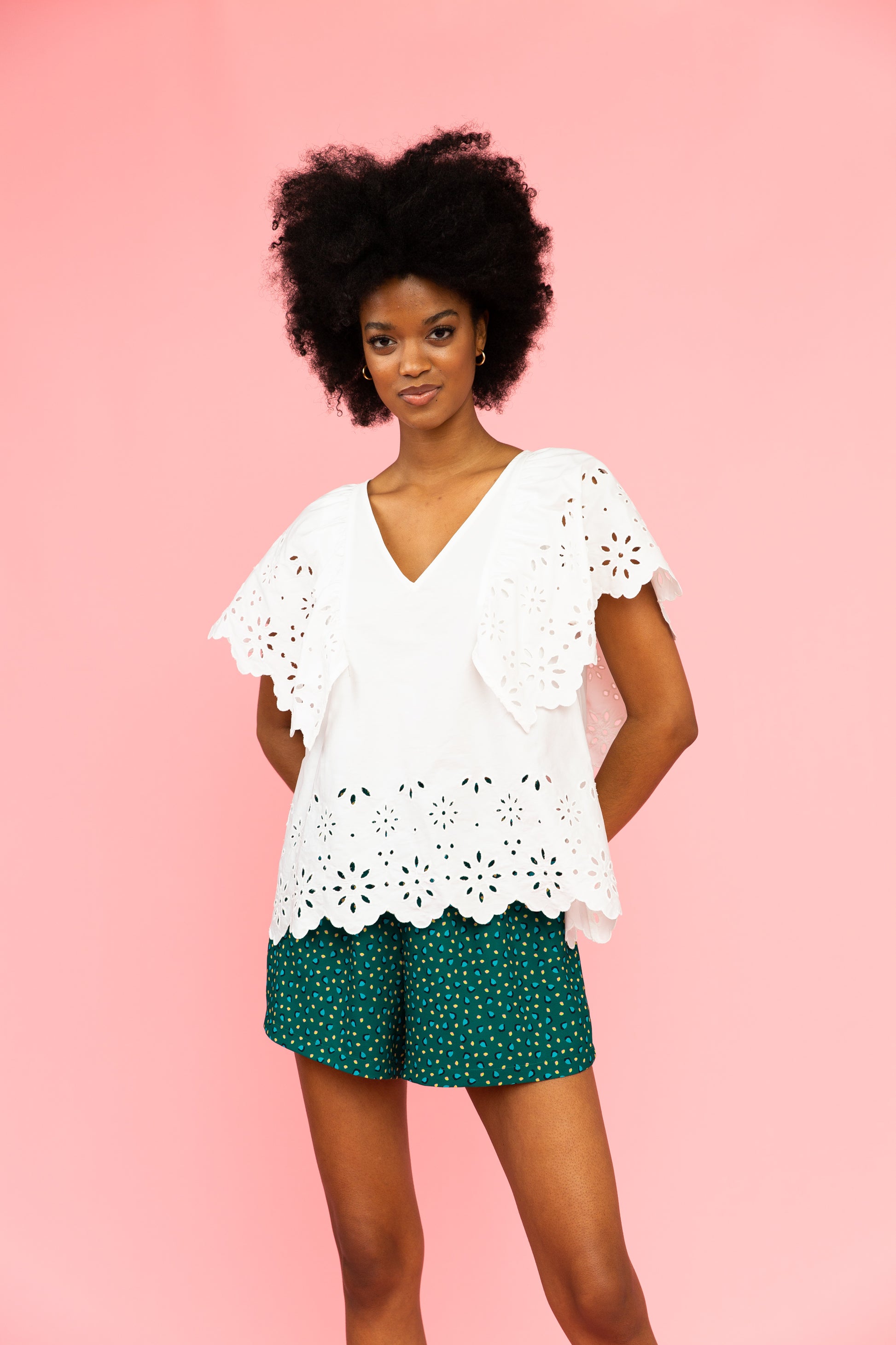 White v-neck top with broderie details and green patterned shorts